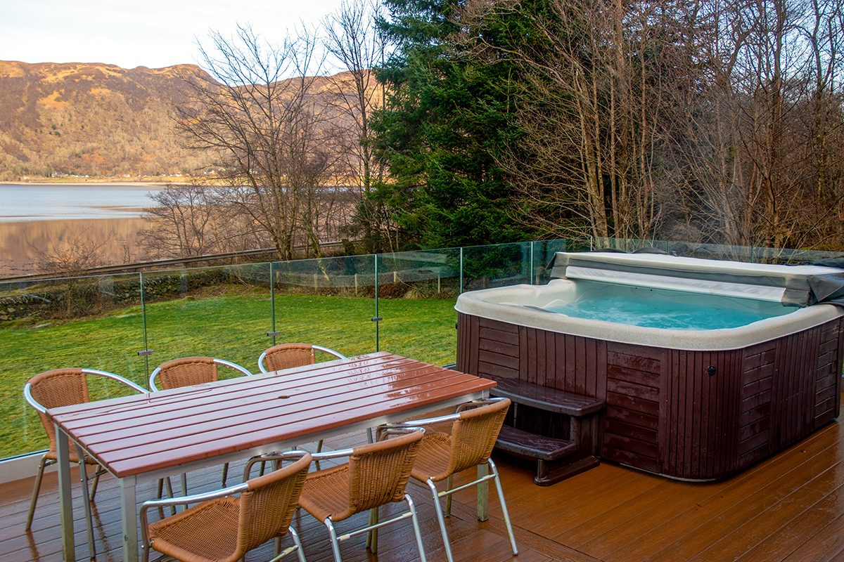 The hot tub and outdoor dining table on the decking at Glenachulish Bay