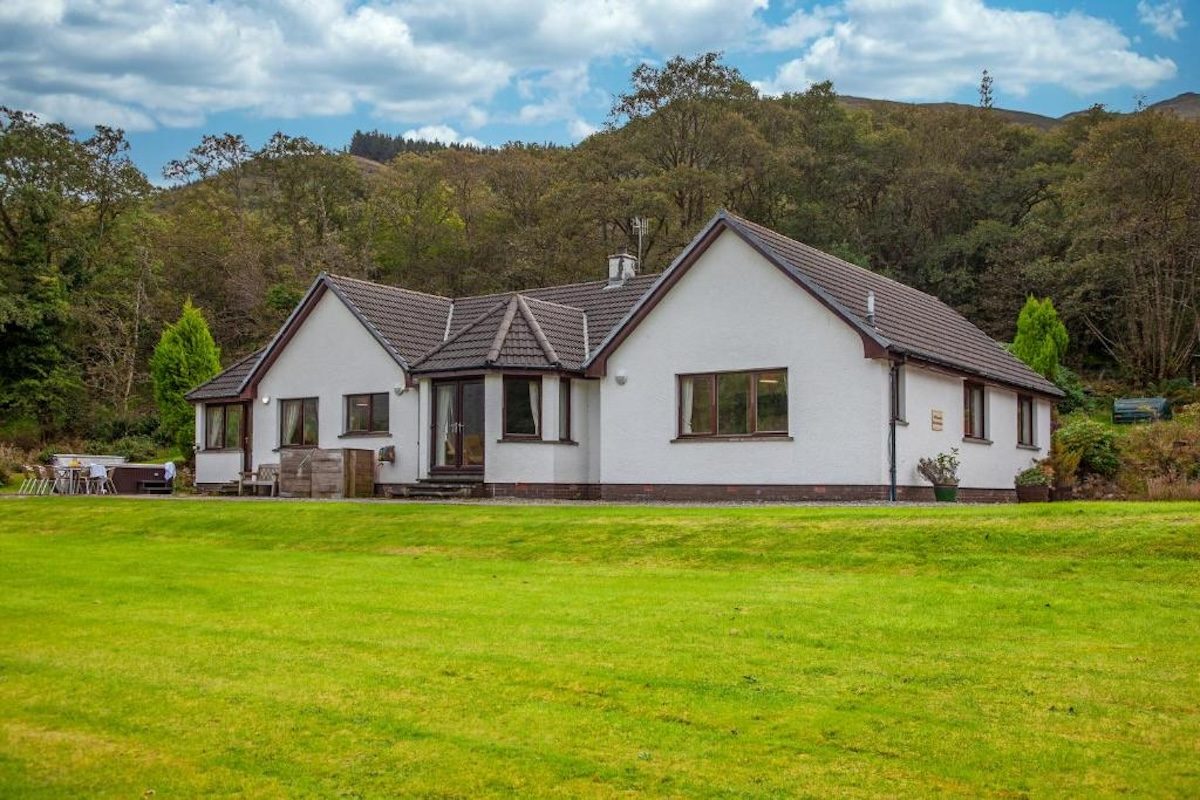 Wildwood farmhouse across its garden with the hillside behind