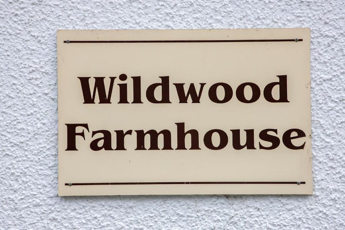The Wildwood Farmhouse sign on the wall of the house