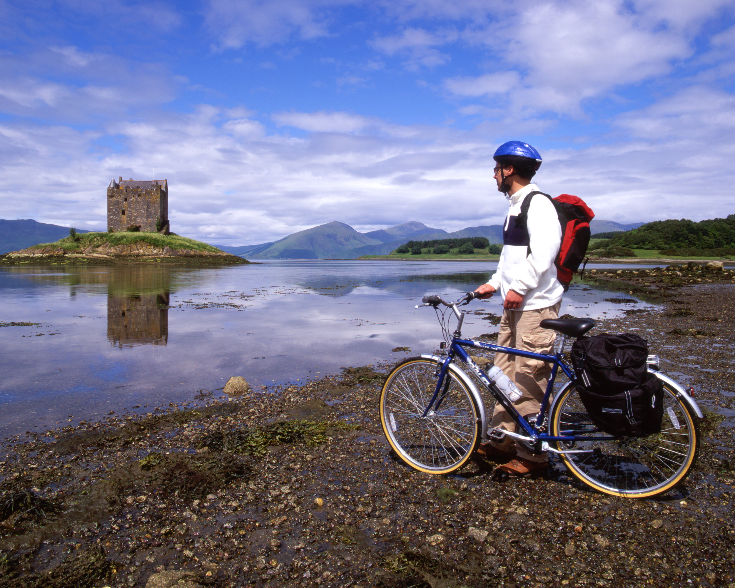 Castle Stalker on its island in Loch Laich, with a cyclist on the shore